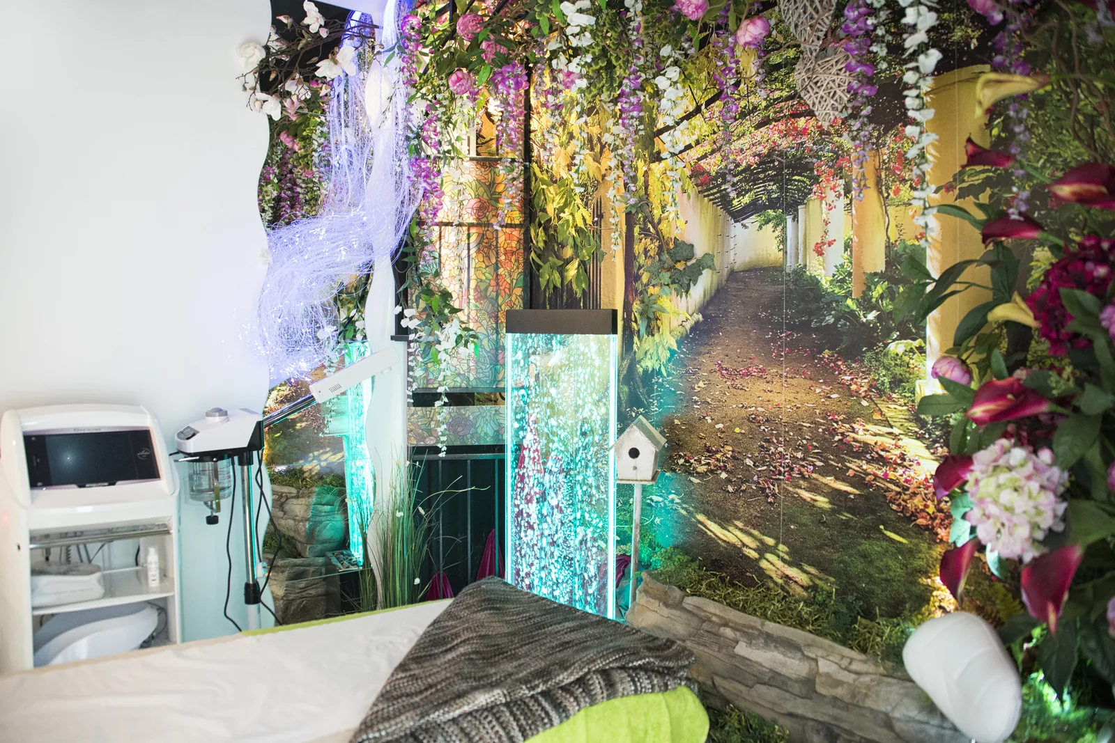 A themed treatment room with a large scenic mural, chandeliers and layered florals